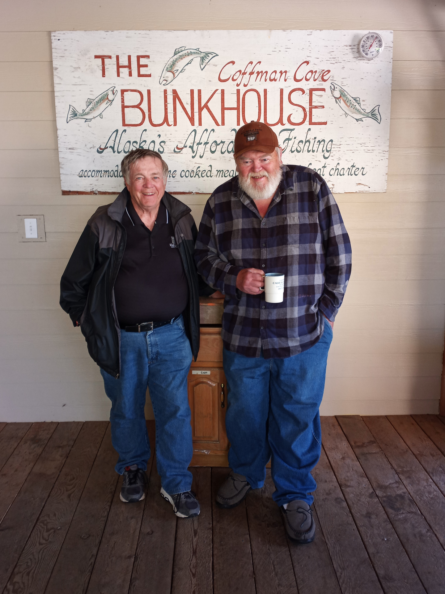 Two guests in front of the Coffman Cove Bunkhouse sign