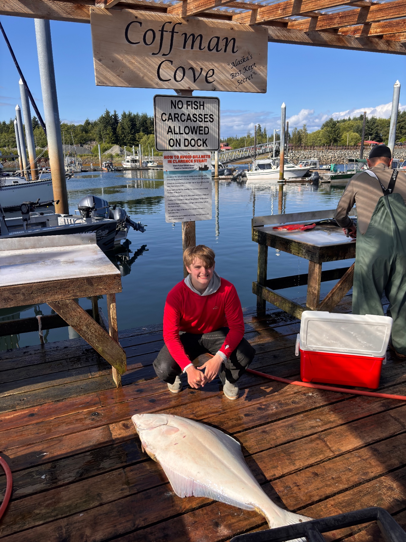 Guest with halibut at the Coffman Cove harbor sign