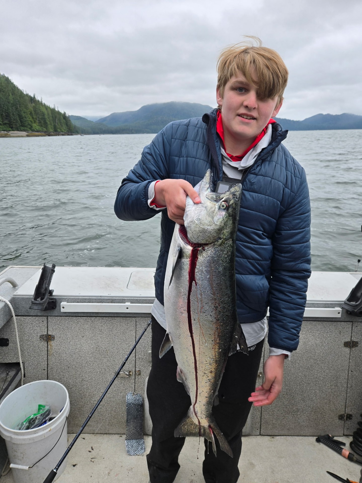 Young angler holding a fresh King salmon on the boat