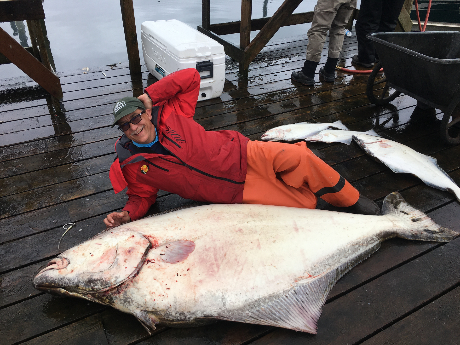 Guest posing beside a giant halibut at the harbor
