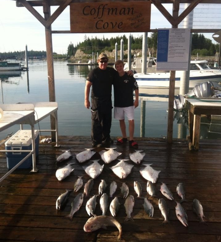 Father and son with a big spread of halibut and rockfish at the Coffman Cove sign