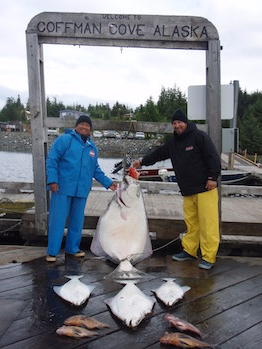 Guests with halibut under the Welcome to Coffman Cove Alaska sign