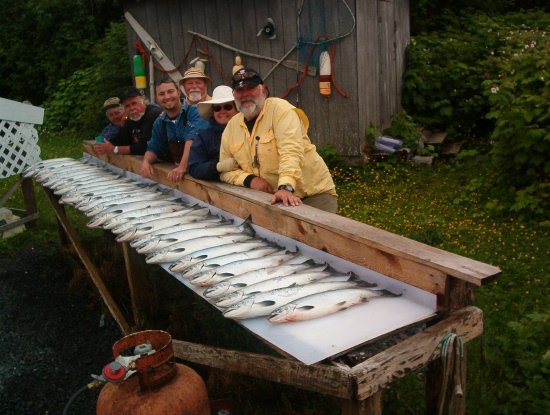 Group behind a long rail of fresh salmon at the cleaning station