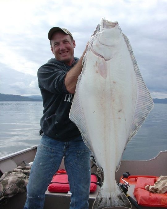 Angler holding up a bright white-belly halibut on the boat